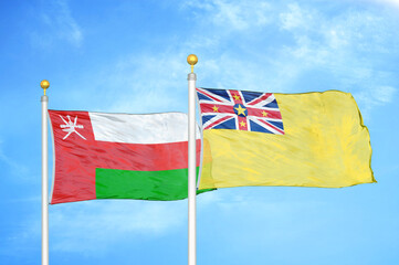 Oman and Niue two flags on flagpoles and blue sky