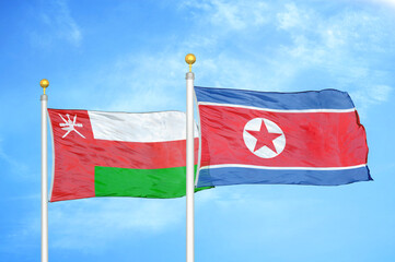 Oman and North Korea two flags on flagpoles and blue sky