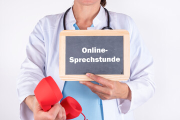 Ärztin in einer Arztpraxis mit einem Telefon und einer Tafel auf der Online-Sprechstunde steht