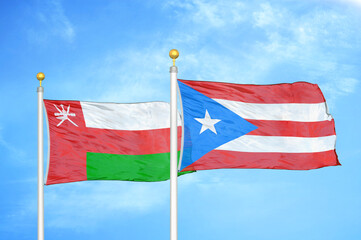 Oman and Puerto Rico two flags on flagpoles and blue sky