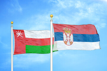 Oman and Serbia two flags on flagpoles and blue sky