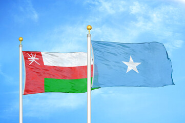 Oman and Somalia two flags on flagpoles and blue sky