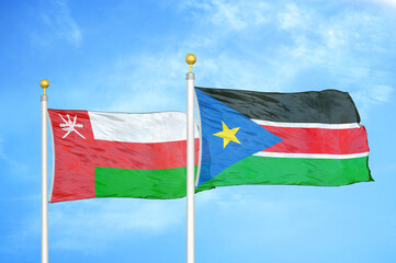 Oman and South Sudan two flags on flagpoles and blue sky