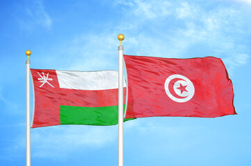 Naklejka na ściany i meble Oman and Tunisia two flags on flagpoles and blue sky