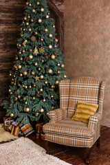 Stylish Christmas interior with a soft armchair or sofa. Comfort home. Christmas tree with presents underneath in living room