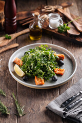 Fresh arugula salad with salmon and olives