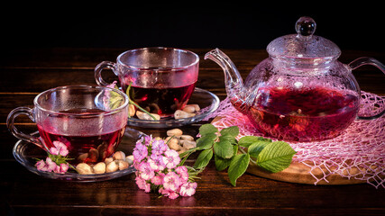 Obraz na płótnie Canvas Tea parties, tea traditions and ceremonies. Zen traditions of the East.Green tea leaves or leaves of medicinal herbs lie on the table with a teapot and mugs of red tea, cashew nuts and clove flowers