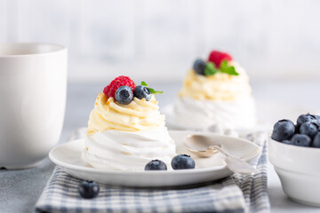 New Zealand Pavlova cake with whipped cream and fresh berries and mug with coffee