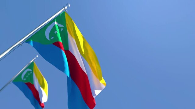 The national flag of Comoros is flying in the wind against a blue sky