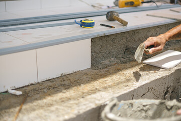 Asian worker laying floor tiles with cement and plaster