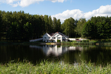 Fototapeta na wymiar White, cozy house on the lake in the forest 