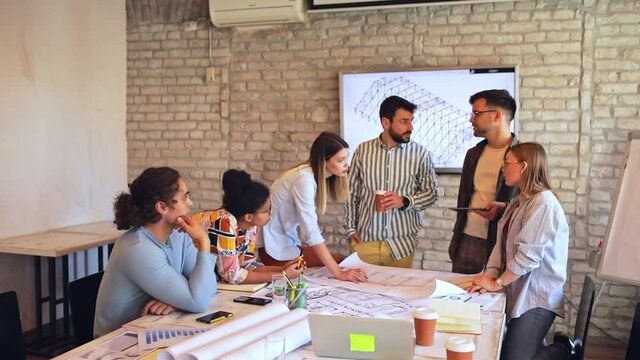 Group of modern business people in casual wear discussing architectural design in the creative office.	