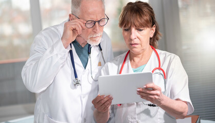 Two doctors discussing about medical report on digital tablet