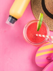 Straw hat, fli flops and red smoothie on pink