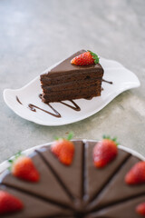 Sliced chocolate cake with fresh strawberries on a white plate.