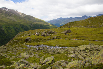 Blick auf eine Hochalm im Langtauferertal mit klienem Bachlauf und Berge im Hintergrund