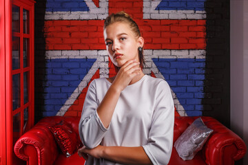 Fashion glamorous portrait of a girl model with white sweater on wall background with a British flag