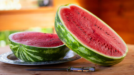 Watermelon in a rustic wooden gazebo on a wooden table. A large red watermelon cut in half. Summer...