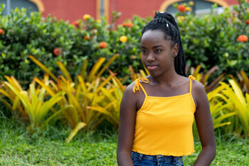 Serious african american young adult woman with dreadlocks in a park