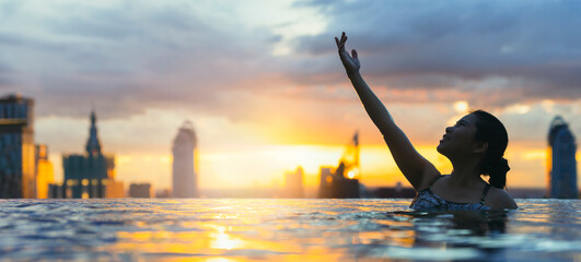 Black silhouette of asian woman splash water on summer vacation holiday relaxing in infinity...