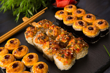 Set of baked sushi rolls with wasabi and ginger on black background. Japanese oriental cuisine