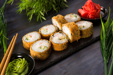 Set of fried sushi rolls with wasabi and ginger on black background. Japanese oriental cuisine