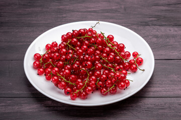 red currants in a white plate on a wooden table
