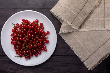 red currants in a white plate on a wooden table