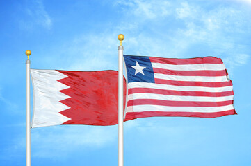 Bahrain and Liberia two flags on flagpoles and blue sky