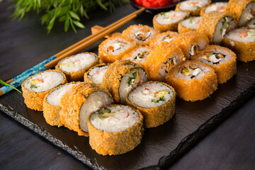Set of fried sushi rolls with wasabi and ginger on black background. Japanese oriental cuisine