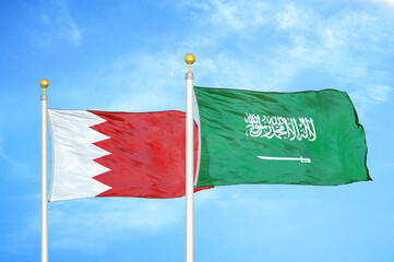 Bahrain and Saudi Arabia two flags on flagpoles and blue sky