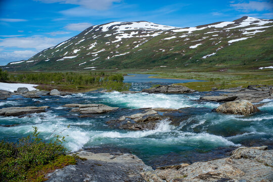 Large turquoise River landscape and Arasluokta sami indigenous people settlement and mountainous valley in Padjelanta national park in northern Sweden with large wild river.