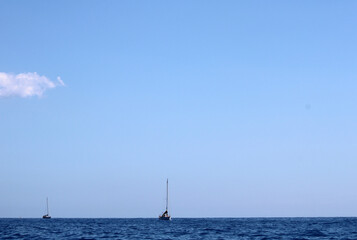 Mare con orizzonte cielo e due barche a vela