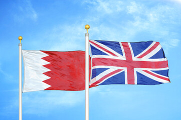 Bahrain and United Kingdom two flags on flagpoles and blue sky