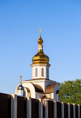 Orthodox church on a background of blue sky. Golden domes of the church in the rays of the setting sun