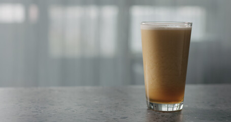 nitro light ale beer with beautiful foam in pint glass on terrazzo countertop with window on background
