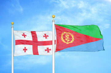 Georgia and Eritrea two flags on flagpoles and blue sky