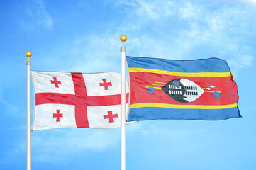 Georgia and Eswatini Swaziland two flags on flagpoles and blue sky