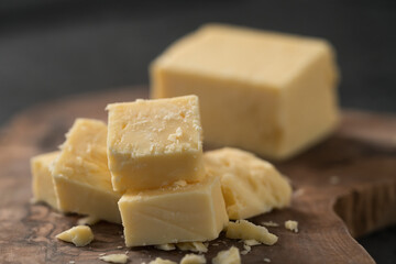 White cheddar cheese pieces on olive wood board