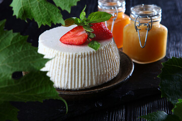 Soft ricotta cheese with strawberries and honey on a black background. The concept of a healthy...