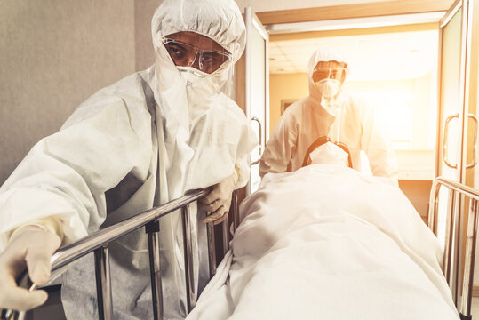 Emergency Medic And Doctor Moving Patient To Emergency Room In Hospital . Doctor Wears Protective Suit And Face Mask In Concept Of Coronavirus And Covid 19 Protection And Quarantine .