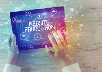 Close-up of a tablet with WEBSITE PRODUCTION inscription, innovative technology concept