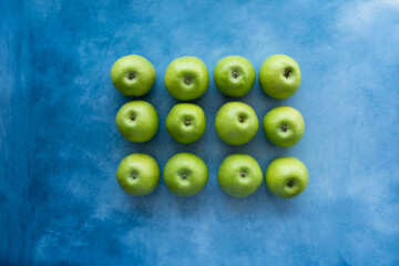 Bright green apples on blue background.