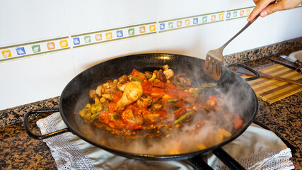 View of the cooking process of a Valencian paella, man is hand removing the ingredients
