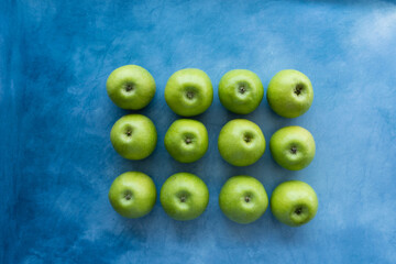 Bright green apples on blue background.