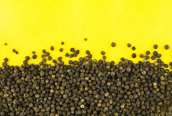 Black pepper on yellow background. Copy space for text.