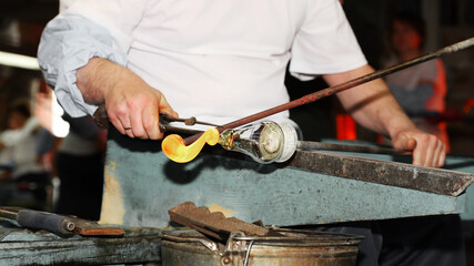 A man manually makes glasses from glass at the factory