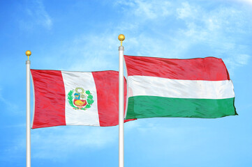 Peru and Hungary two flags on flagpoles and blue sky