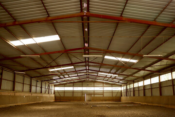 Empty riding hall with sandy covering without riders as an equestrian background