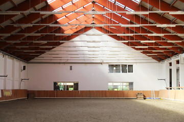 Empty riding hall with sandy covering without riders as an equestrian background